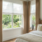 A full-length shot from an angle showing a pair of Adrian Cashmere Blackout Curtains in Camel Yellow framing a two-panel, white-framed window.