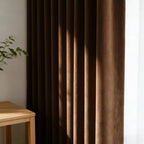 A focused medium shot inside the bedroom, showcasing the curtain panel hanging neatly beside a classic ceramic bedside lamp and a decorative floral pillow.