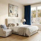 An alternate perspective of the bedroom setup, emphasizing the classic blue ceramic lamp on the nightstand right next to the neatly draped deep sea blue curtain panel.