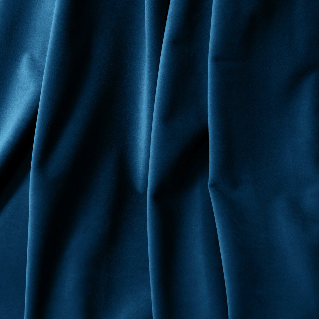 A macro close-up focusing on the luxurious, heavy folds of the deep sea blue material, highlighting its soft, velvet-like texture and subtle matte finish.