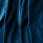 A macro close-up focusing on the luxurious, heavy folds of the deep sea blue material, highlighting its soft, velvet-like texture and subtle matte finish.