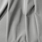 A detailed close-up capturing the graceful vertical drapes, soft texture, and subtle shadows of the light gray curtain material.
