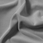 A macro close-up view showcasing the smooth, soft texture and luxurious, organic folds of the light gray blackout fabric.