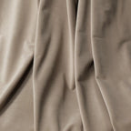 A beautiful overhead shot of the Light Gray-Brown Adrian Cashmere Blackout Curtain fabric artistically draped to showcase its heavy, high-quality material and soft sheen.