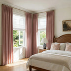 A wide-angle interior shot of the entire bedroom layout, showcasing multiple pink curtain panels framing the windows in a bright, sunlit space.