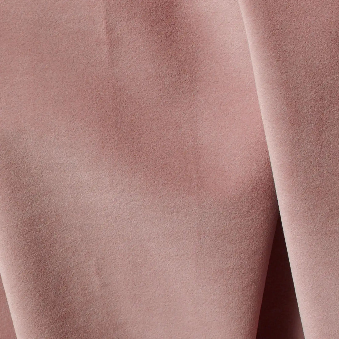 An extreme macro photograph highlighting the fine, velvet-like surface texture and luxurious weave of the pink curtain fabric.