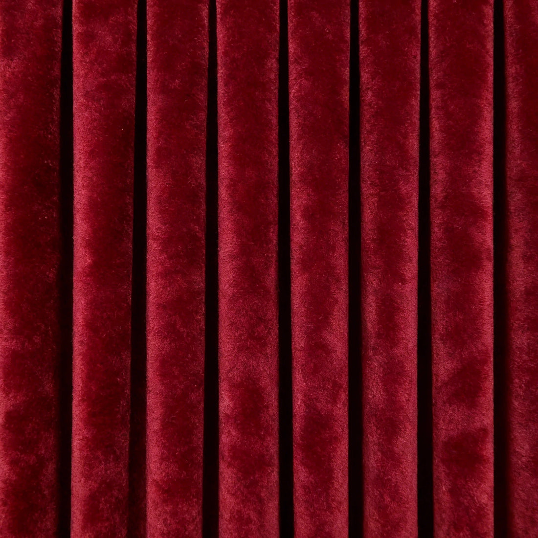 A tight, direct shot showing the crisp, uniform vertical pleats and deep, luxurious coloration of the hanging curtain panel.