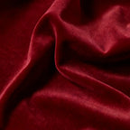 An elegant macro photograph showcasing the ultra-soft, velvet-like surface texture and gentle, sophisticated sheen of the ruby red material.