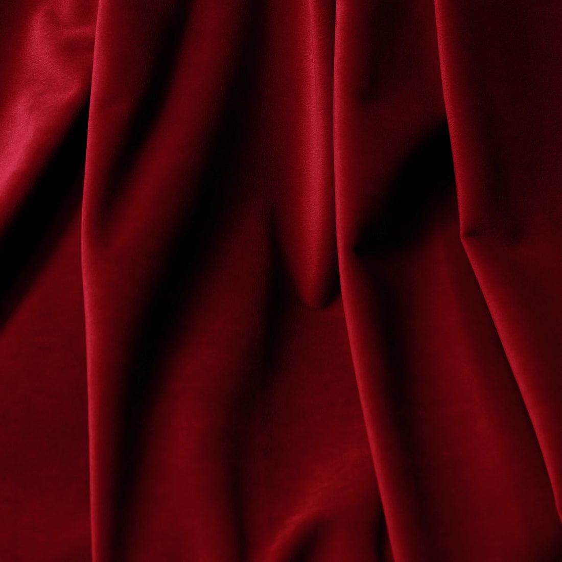 A beautiful close-up of the ruby red fabric cascading in rich, dramatic folds to illustrate its heavy weight, light-blocking density, and premium texture.