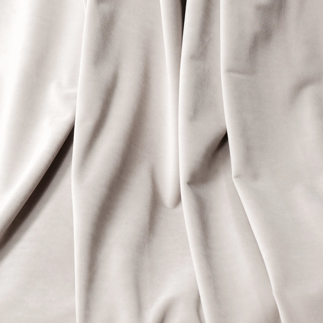 A macro close-up texture shot of the off-white cashmere blackout curtain fabric, showcasing its soft, velvet-like surface and elegant, fluid folds.