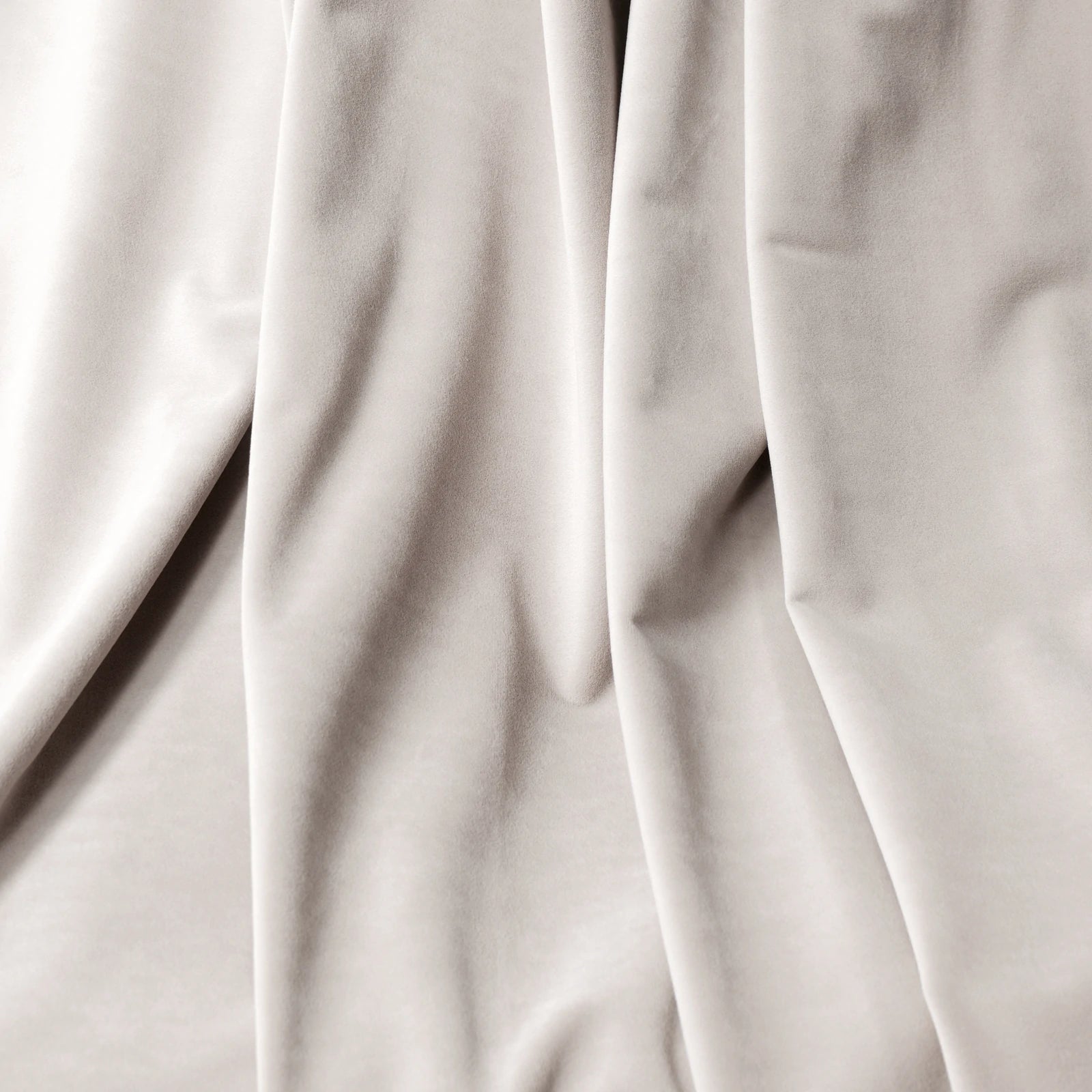 A macro close-up texture shot of the off-white cashmere blackout curtain fabric, showcasing its soft, velvet-like surface and elegant, fluid folds.