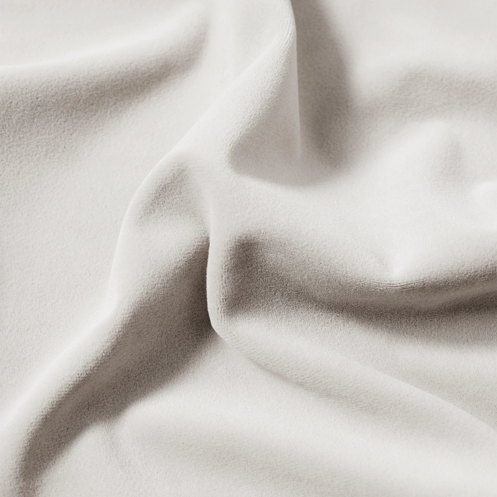 A detailed close-up view of the off-white curtain material, emphasizing the heavy, high-quality drape of the fabric and its smooth, undulating folds under gentle lighting.
