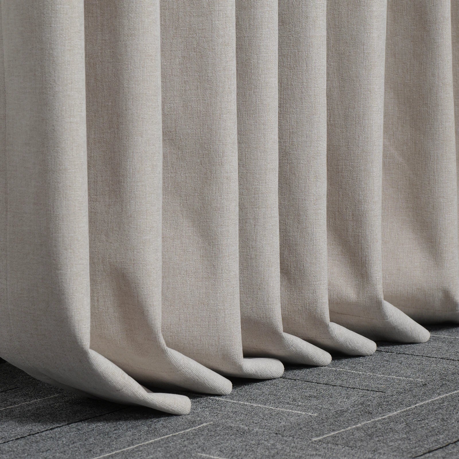 Beige Alex blackout curtain hems pooling neatly on a dark tiled floor