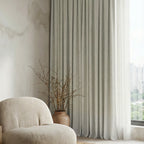 Close view of off-white Alex curtain folds beside a lounge chair and dried branches