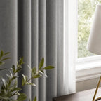 Close view of cool gray Gavin curtain folds beside a sunlit window and plant