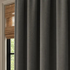 Close view of dark gray Gavin curtain folds beside a sunlit window and plant