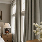 Close view of gray brown Gavin curtain folds beside a sunlit window and plant
