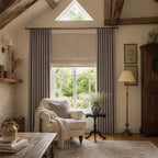 Purplish gray Gavin curtains framing a bright neutral bedroom with brass rods