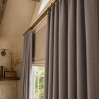 Close view of purplish gray Gavin curtain folds beside a sunlit window and plant