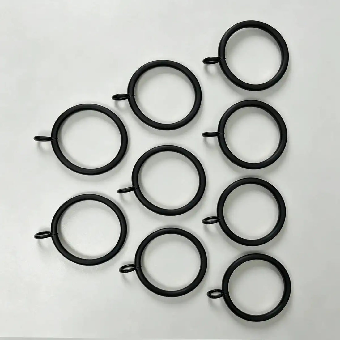 Close-up of black steel curtain rings with attached loops, showing size and design for hanging curtains, SKU: AGPC70-1