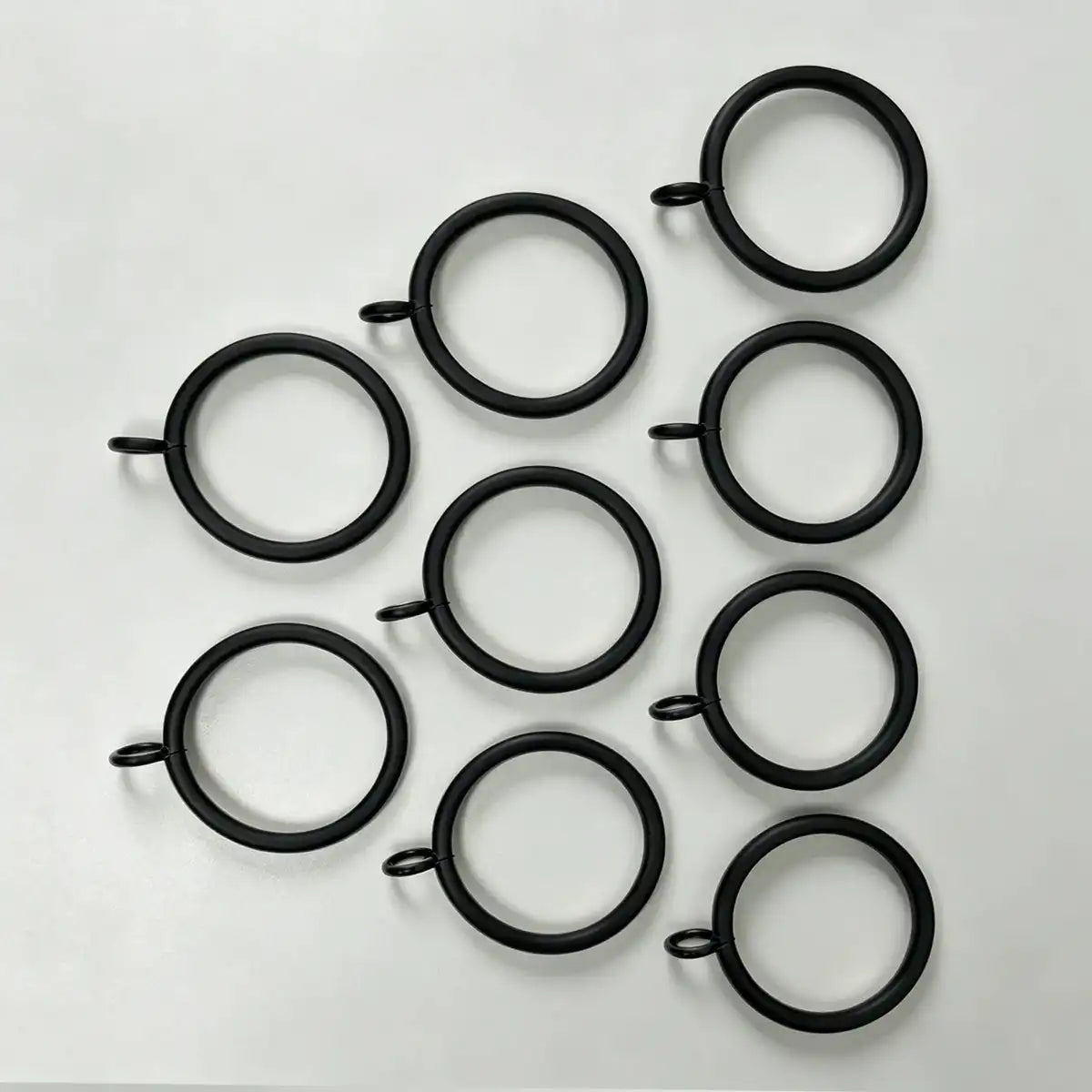 Close-up of black steel curtain rings with attached loops, showing size and design for hanging curtains, SKU: AGPC70-1
