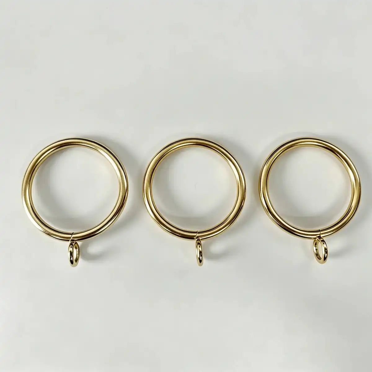 Close-up of gold steel curtain rings with small attachment loops, ideal for window treatment accessories and drapery hanging