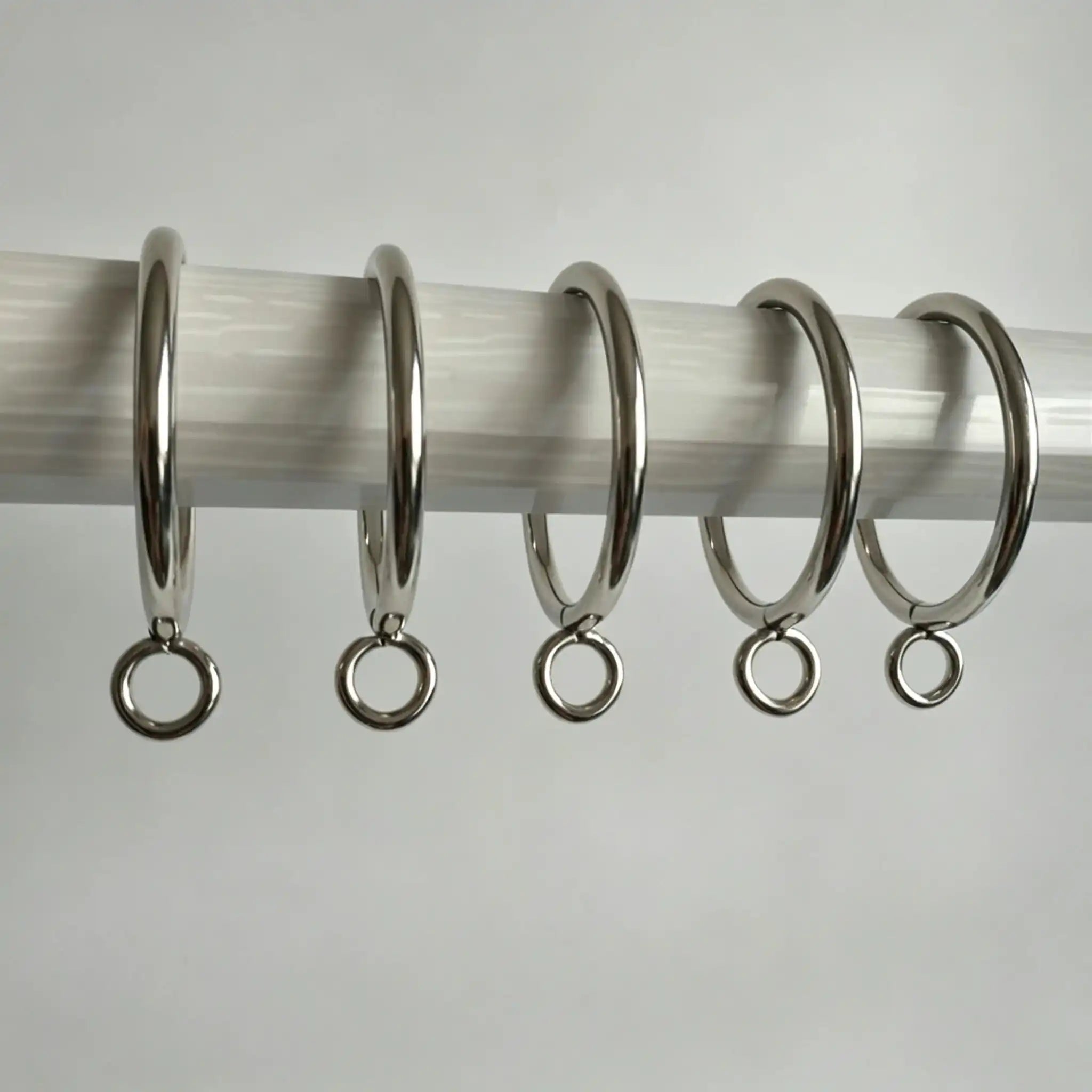 Stainless steel curtain rings with hooks arranged on a white surface, shiny and durable, ideal for window treatments, SKU: AGPC70-1