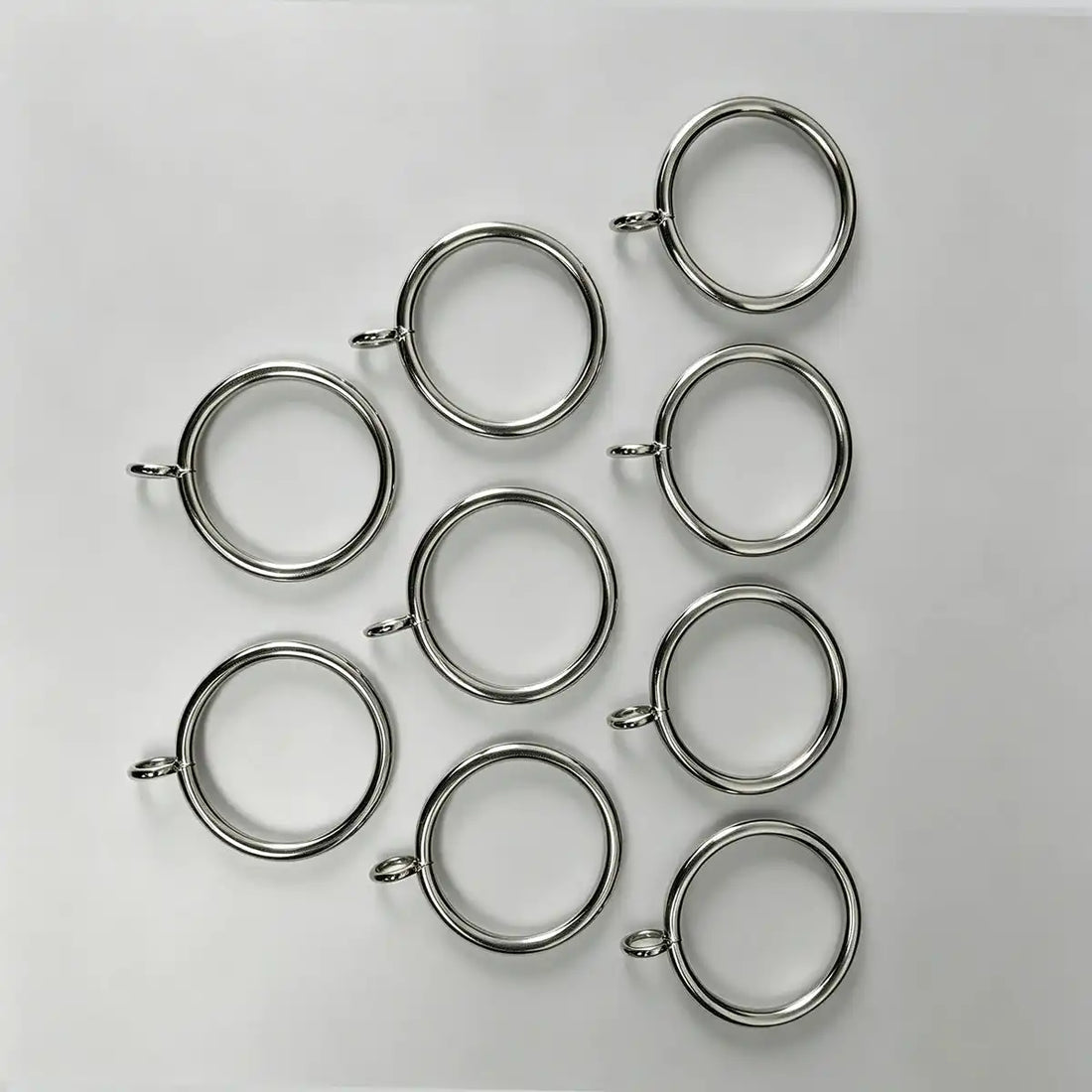 Close-up of stainless steel curtain rings with small loops, measuring 1 1/2 inches in diameter, used for hanging curtains