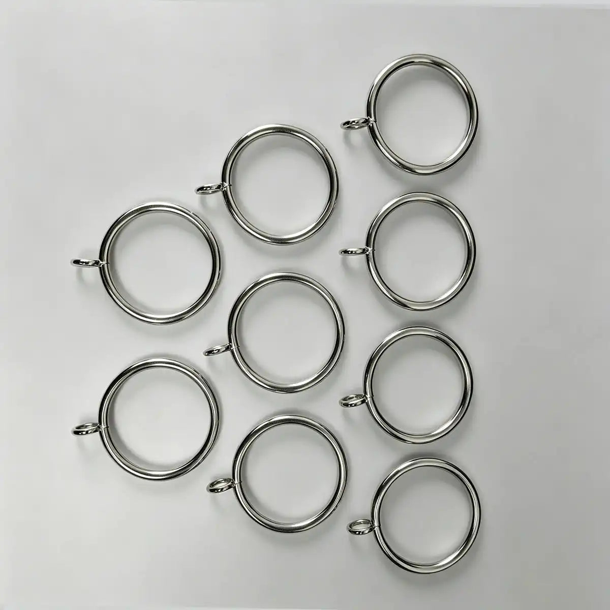 Close-up of stainless steel curtain rings with small loops, measuring 1 1/2 inches in diameter, used for hanging curtains