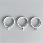 Close-up of white steel curtain rings with loops, arranged on a flat surface, used for fixing curtain spacers, SKU: AGPC70-1