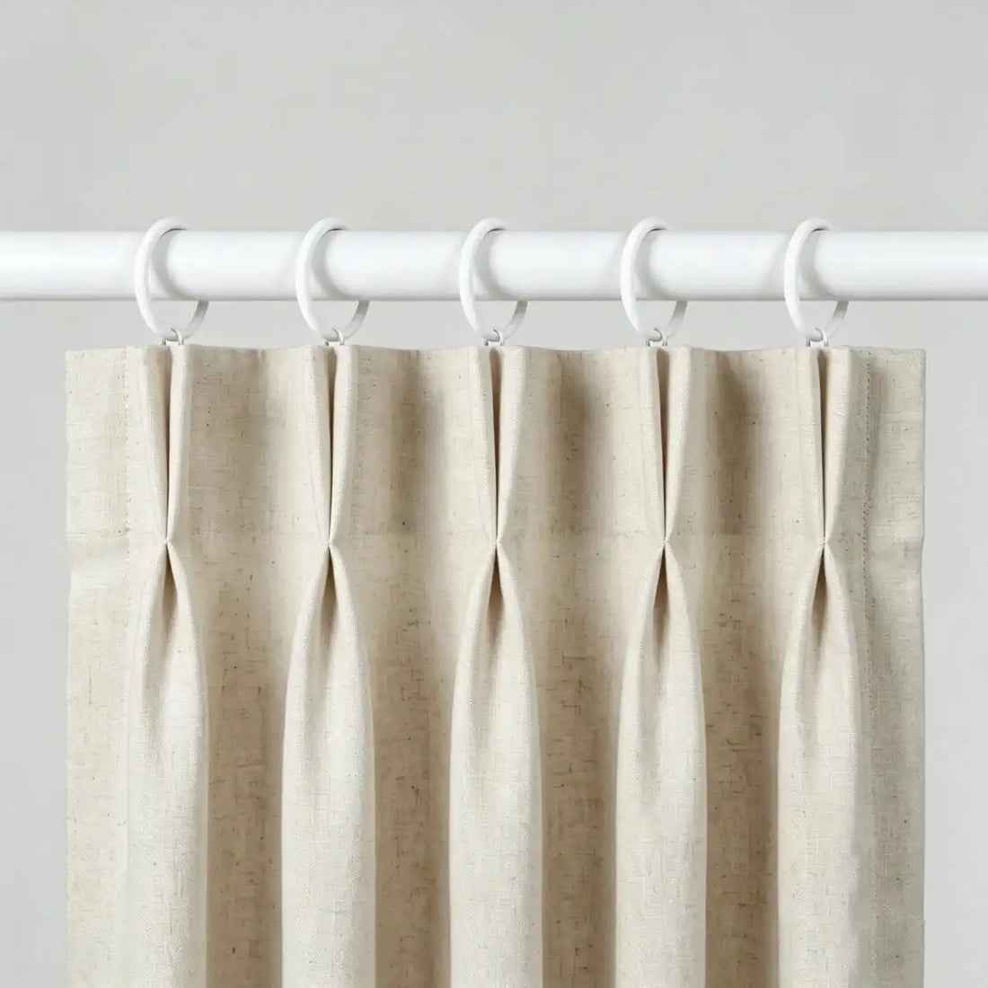 White fabric curtain with white metal rings for easy hanging, mounted on a white curtain rod for home window decor