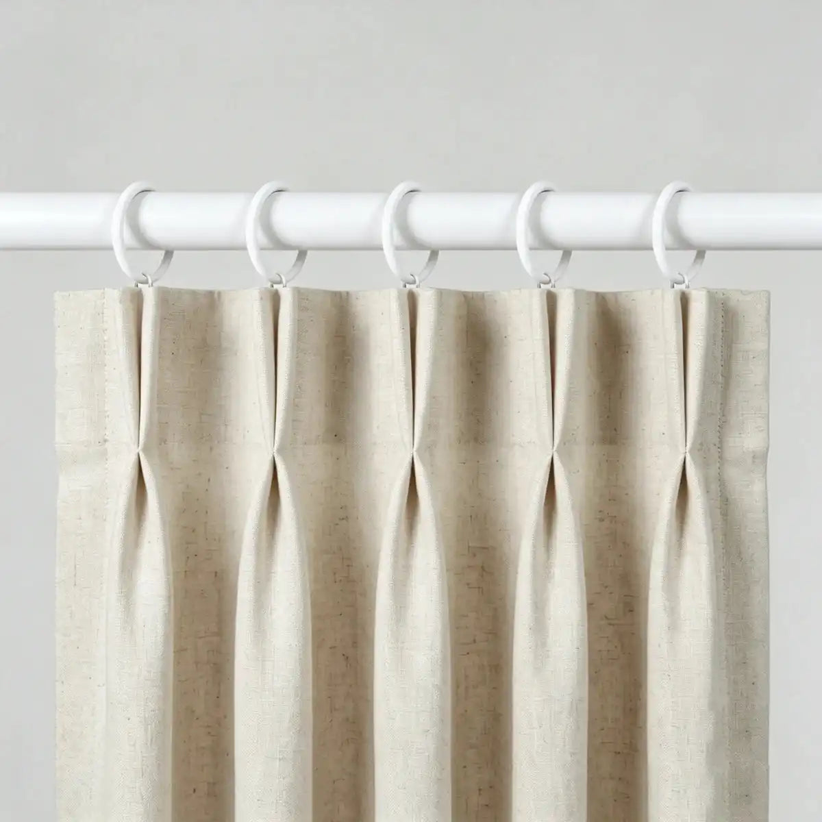 White fabric curtain with white metal rings for easy hanging, mounted on a white curtain rod for home window decor