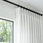 Detailed view of black rod rings holding the precise pinch pleat header of White John Linen Texture Cotton Curtains