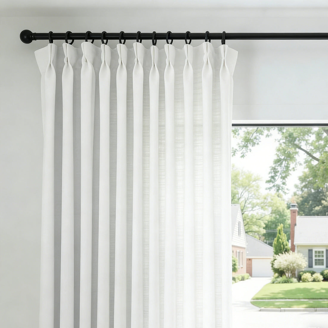 Dove White John Linen Texture Cotton Curtains with tailored pinch pleats hanging on a black curtain rod against a bright window