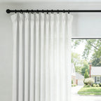 Dove White John Linen Texture Cotton Curtains with tailored pinch pleats hanging on a black curtain rod against a bright window