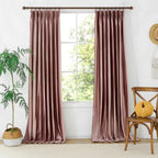 Pink velvet curtains hanging in front of a large window with greenery outside, decorated with a small yellow pouf and a cozy window seat