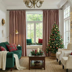 Pink velvet curtains hanging in front of a large window with greenery outside, decorated with a small yellow pouf and a cozy window seat