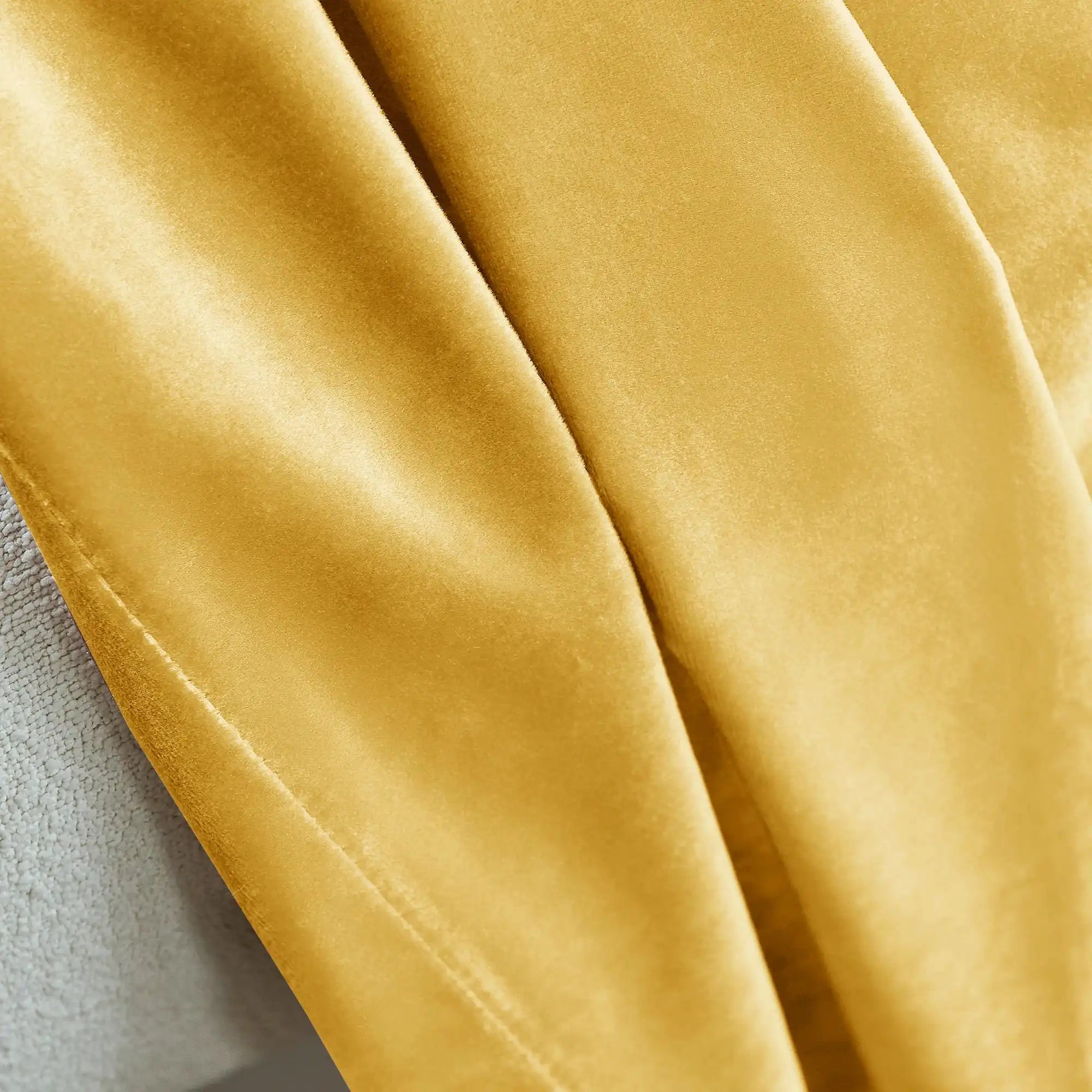 Detailed view of yellow velvet fabric with a smooth, velvety surface, showcasing the rich texture and luxurious quality of the curtains