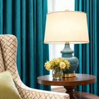 Teal velvet drapes with a pearl-embellished curtain rod, adding a touch of sophistication to a stylish living room setting.