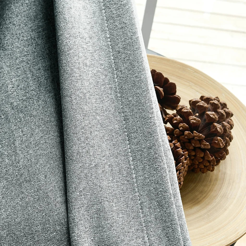 Fabric texture close up of White Gray Orion Linen Look 100 percent Blackout Curtains next to pinecones