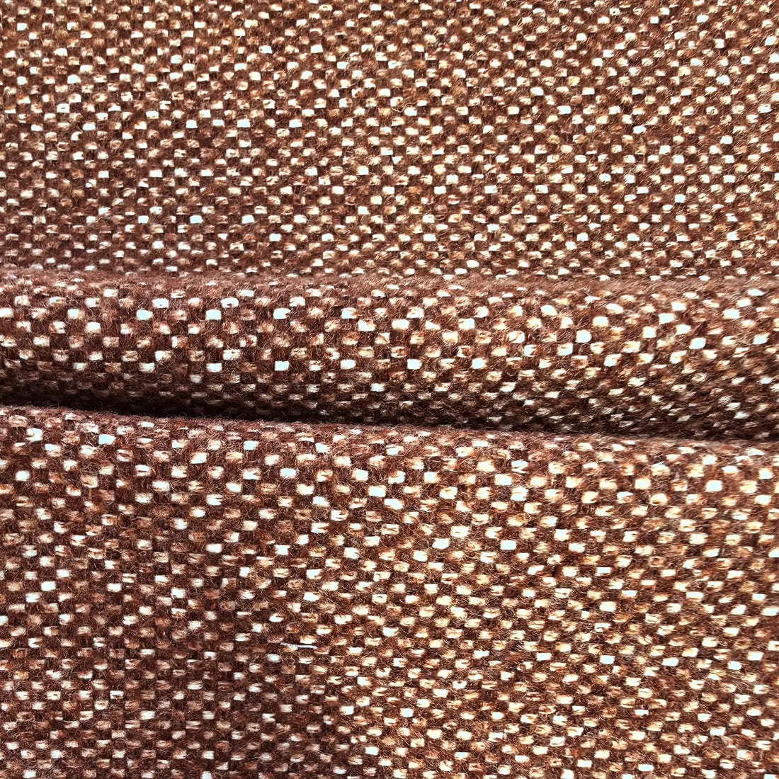 A close-up view of the multi-tonal caramel and white curtain fabric, neatly pressed into a horizontal fold across the middle to showcase its clean drape and uniform texture.