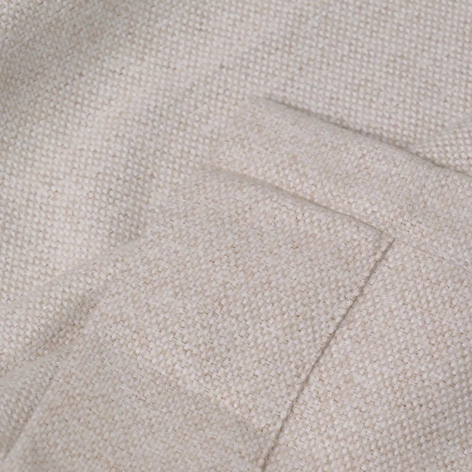 A close-up view of the light yellow, oatmeal-textured fabric showing a neatly stitched hemmed edge, highlighting the high-quality, dense weave of the material.