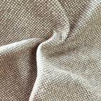 A close-up view of the grayish-brown textile gathered into soft, organic ripples, highlighting the heavy drape, light-catching weave, and multi-tonal yarn details.