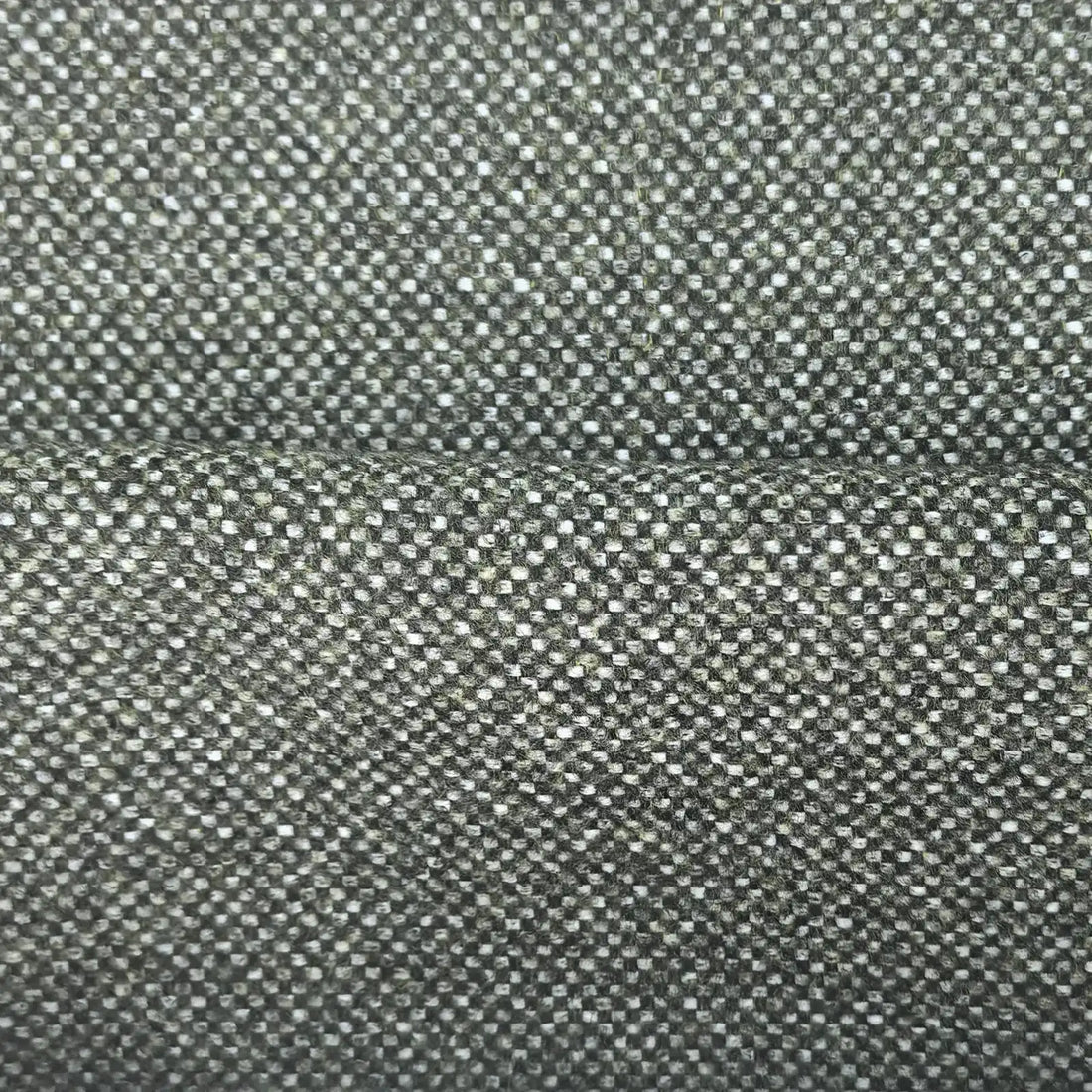 A close-up, full-frame shot of the forest green fabric showing a soft horizontal ridge or fold across the center. The detailed basketweave pattern reveals a tight, intricate mix of dark green, sage, and off-white threads.