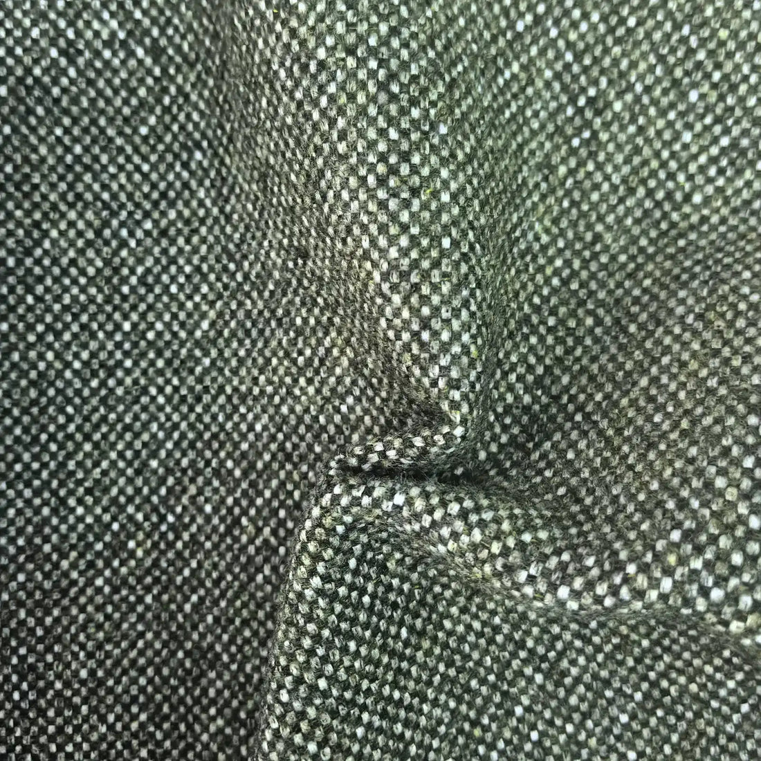 A tactile texture shot of the deep green fabric gathered into heavy, organic folds and ripples, highlighting the material's premium thickness, natural drape, and multi-tonal woven quality.