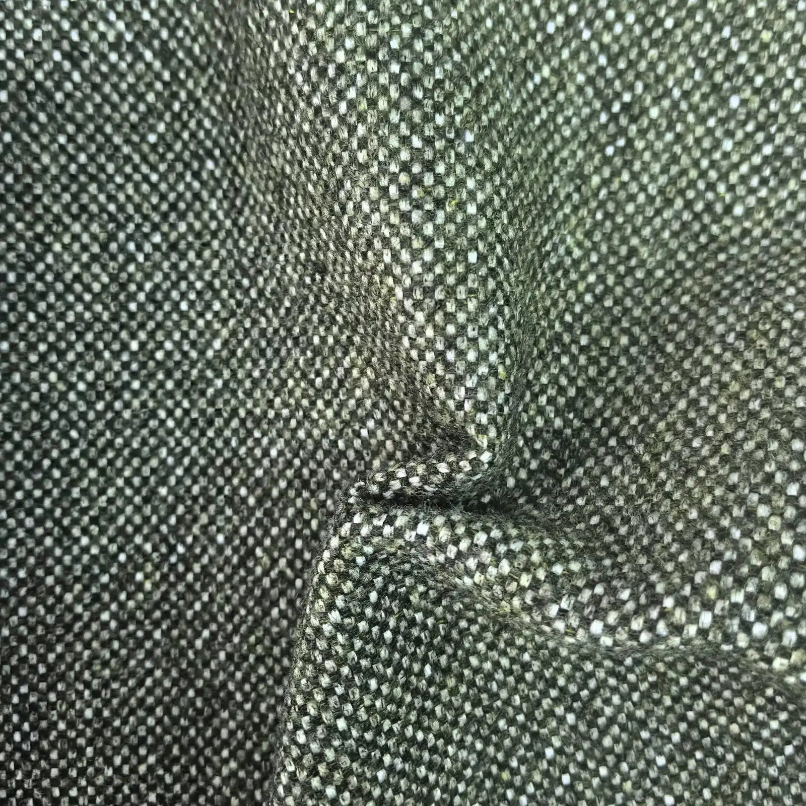 A tactile texture shot of the deep green fabric gathered into heavy, organic folds and ripples, highlighting the material's premium thickness, natural drape, and multi-tonal woven quality.