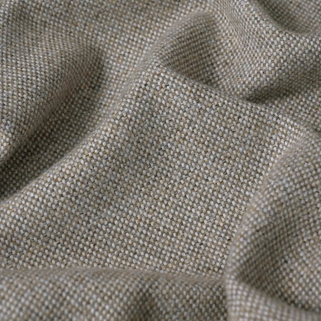 A close-up, full-frame shot of the light gray fabric, showcasing its textured, multi-tonal basketweave pattern with a mix of beige, white, and gray threads. The fabric is softly undulating with organic ripples and shadows.