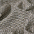 A close-up, full-frame shot of the light gray fabric, showcasing its textured, multi-tonal basketweave pattern with a mix of beige, white, and gray threads. The fabric is softly undulating with organic ripples and shadows.