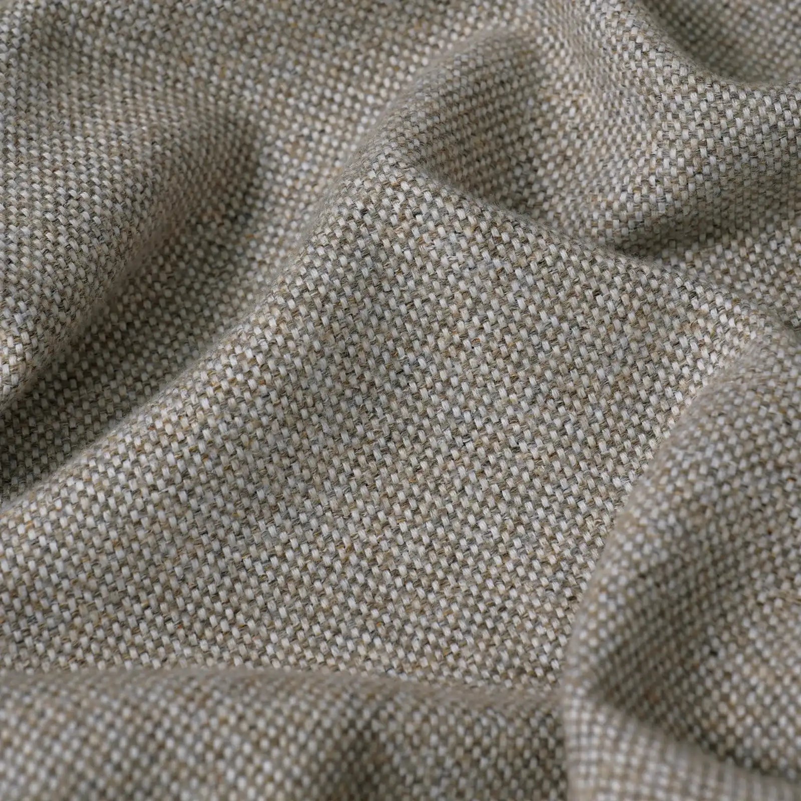 A close-up, full-frame shot of the light gray fabric, showcasing its textured, multi-tonal basketweave pattern with a mix of beige, white, and gray threads. The fabric is softly undulating with organic ripples and shadows.