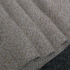 A close-up texture shot of the light gray heathered fabric arranged in tight, soft folds, emphasizing the weight, quality, and detailed yarn structure of the material.